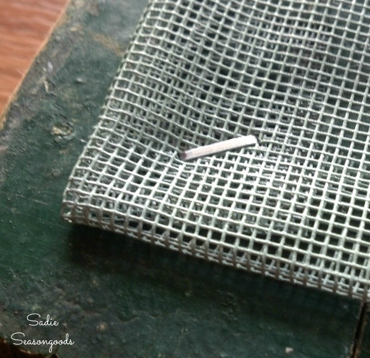 Stapling a screen to vintage window frames for displaying the lace doilies