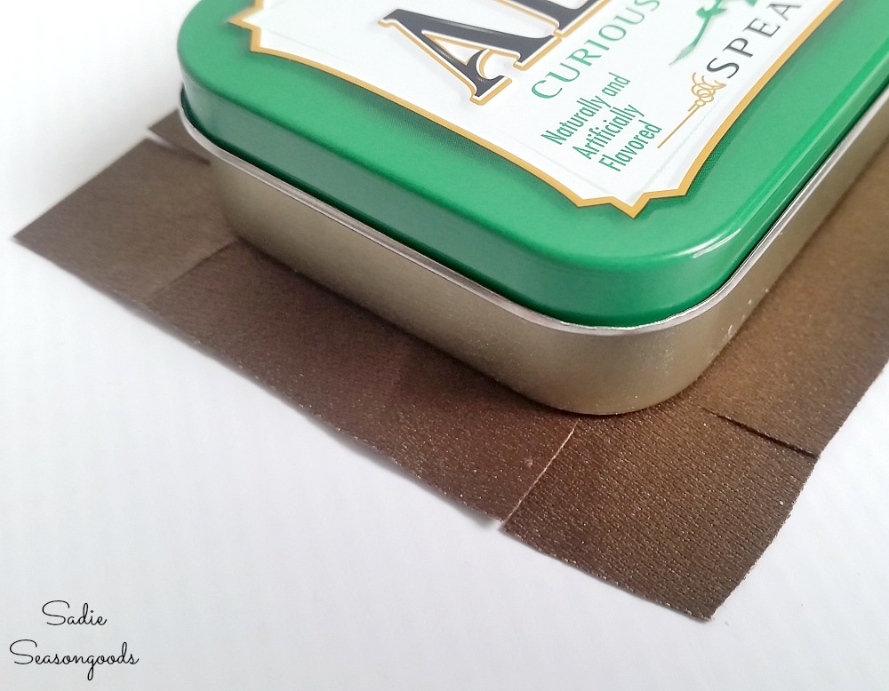 How to cover the corners of a mints tin with fabric by making perpendicular cuts to the Altoids tin