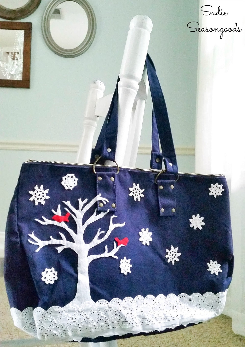 Snowflake doilies in a snowy scene on a blue canvas bag