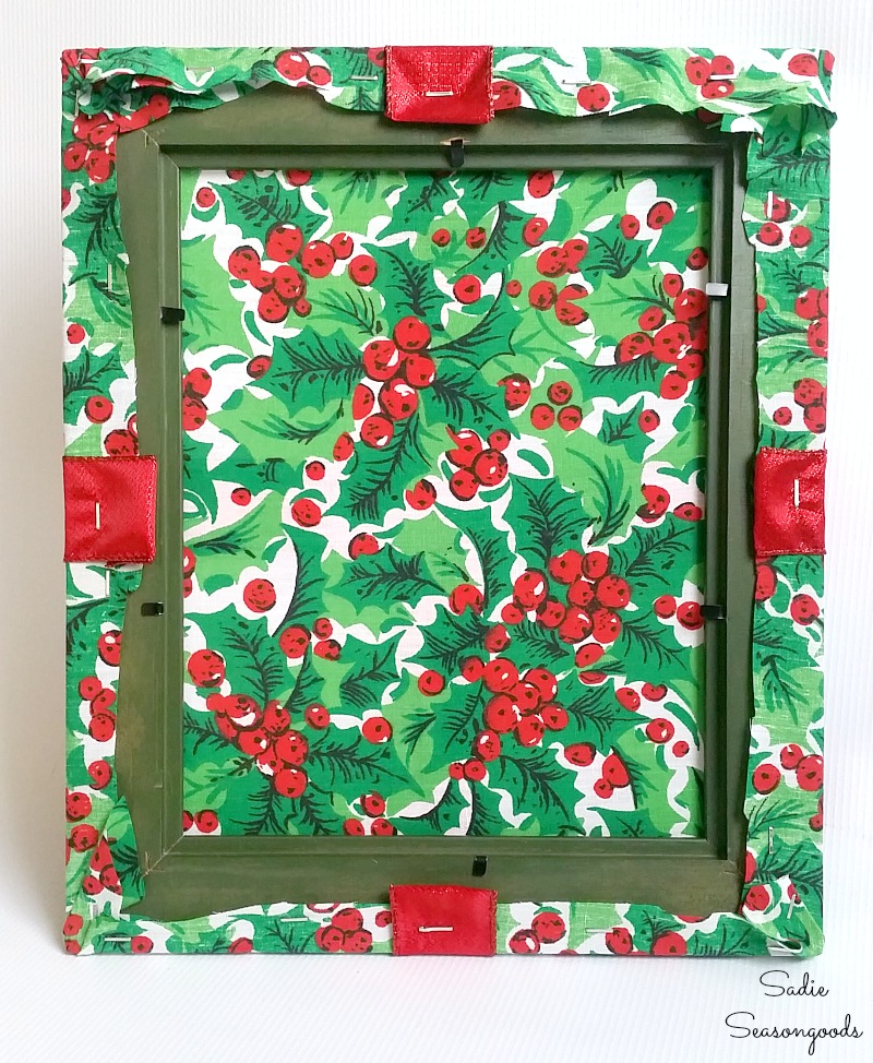Using a staple gun to attach the Christmas ribbon into the back of a wooden photo frame by Sadie Seasongoods