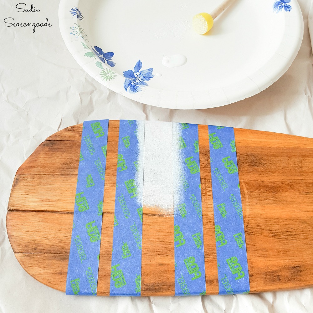 Masking tape as stencils for painting stripes on a wooden paddle