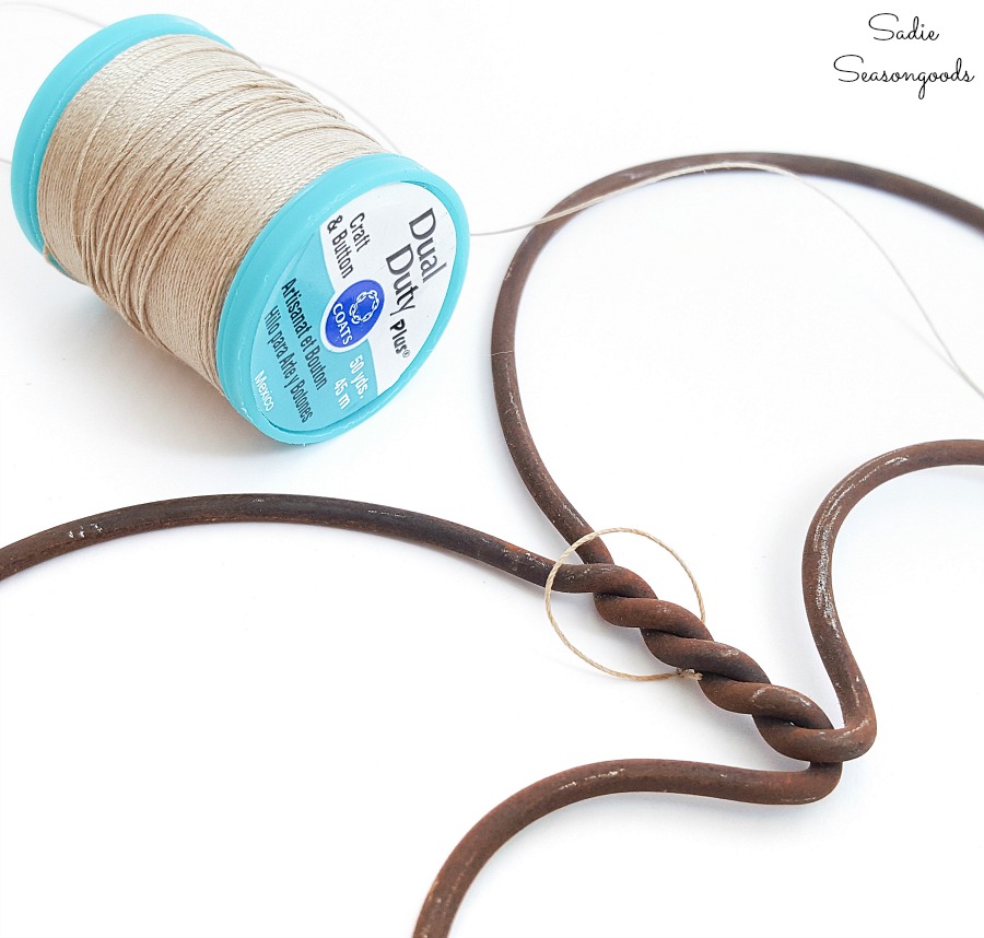 Tying a loop of craft thread to a rug beater to use as heart decorations for Valentines Day decor