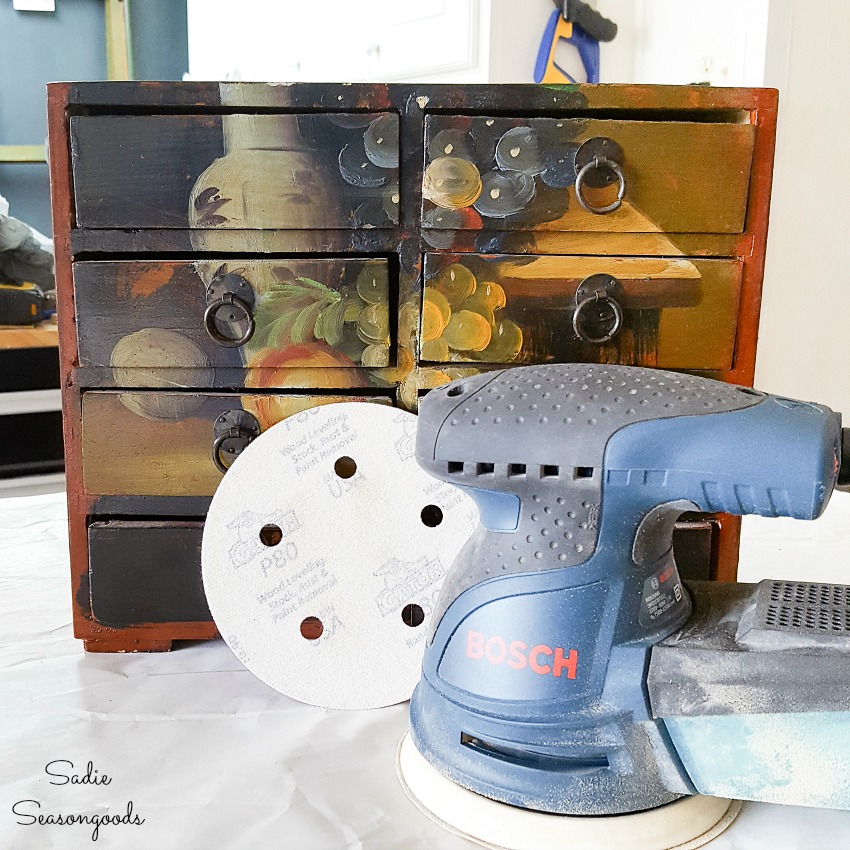 Bosch orbital sander to remove the paint from a small wooden chest