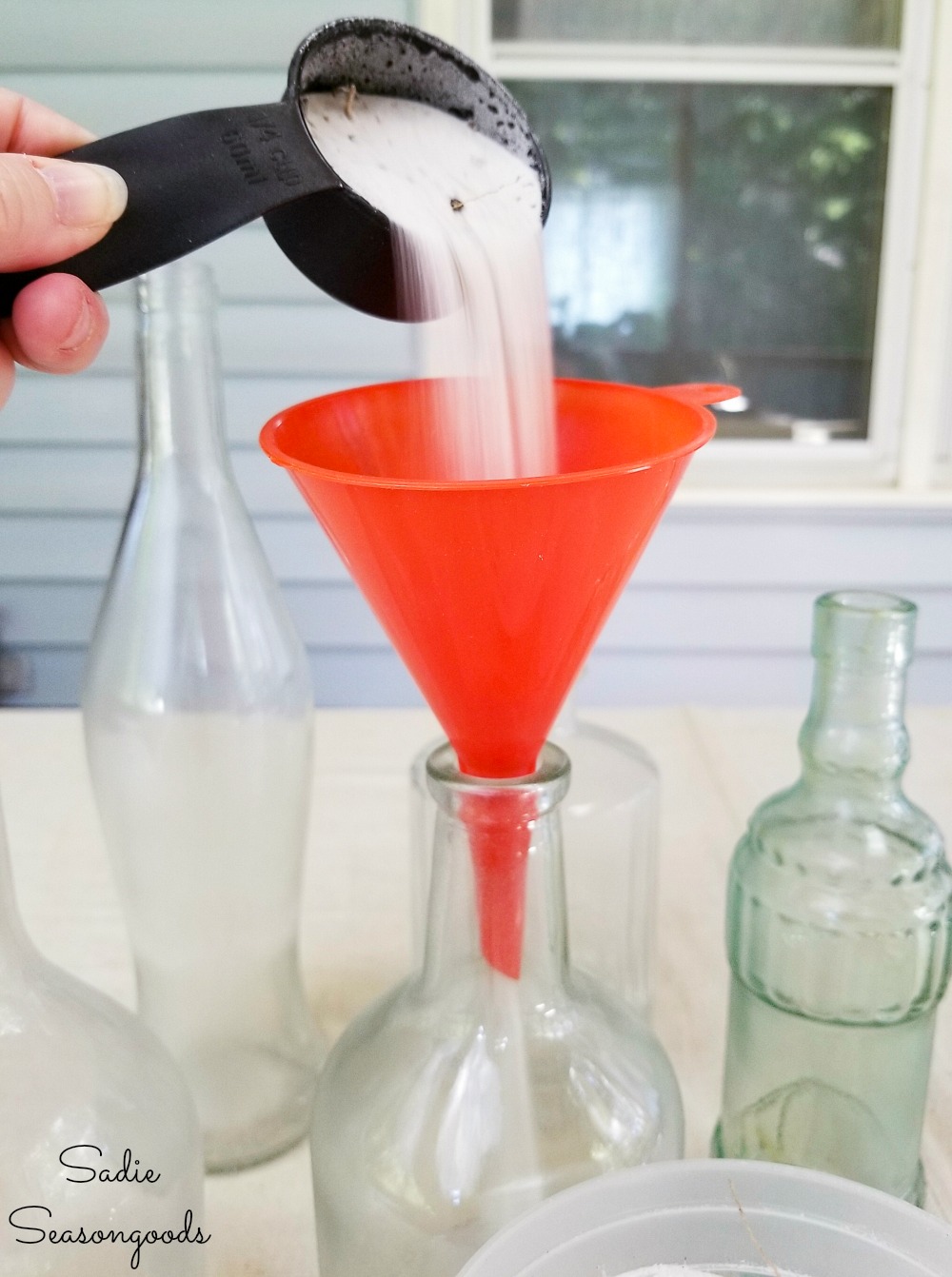 Pouring the beach sand into the empty wine bottles