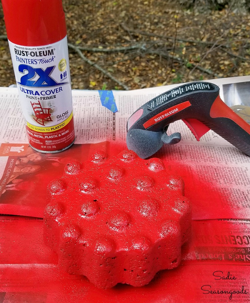 Spray painting the decorative garden stones or concrete lawn ornaments