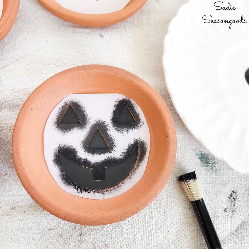 using a jack o lantern face stencil to make a pumpkin coaster