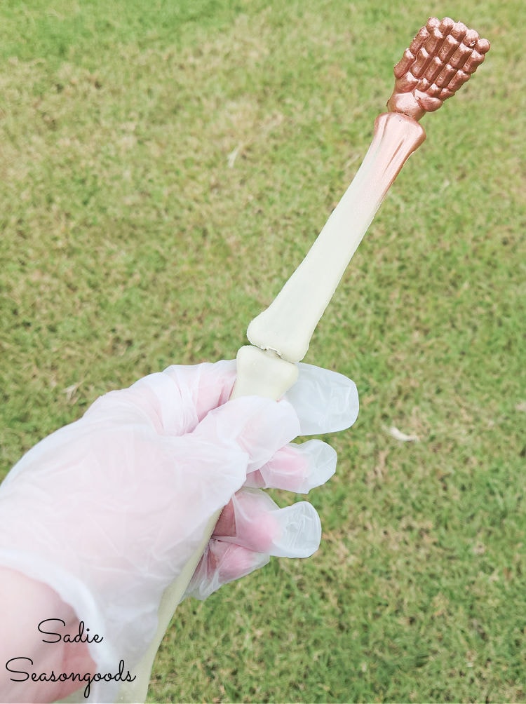 holding the leg of a plastic skeleton in order to paint the feet