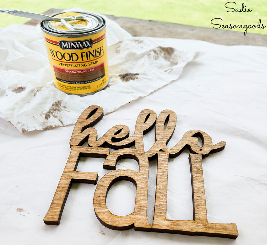 staining a hello fall sign before attaching it to woven decor