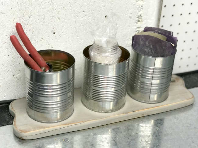 diy organizer with tin cans on a cutting board