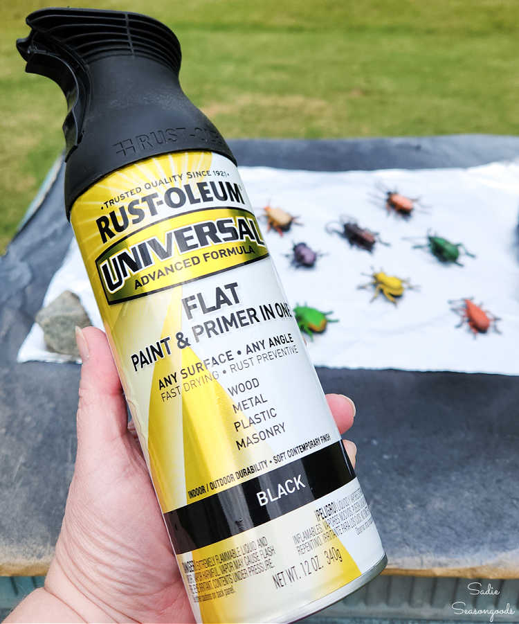 spray painting plastic beetles with flat black paint