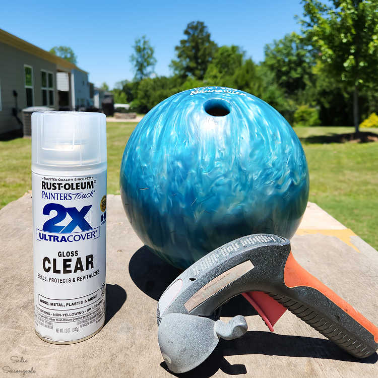 spraying a used bowling ball with glossy topcoat